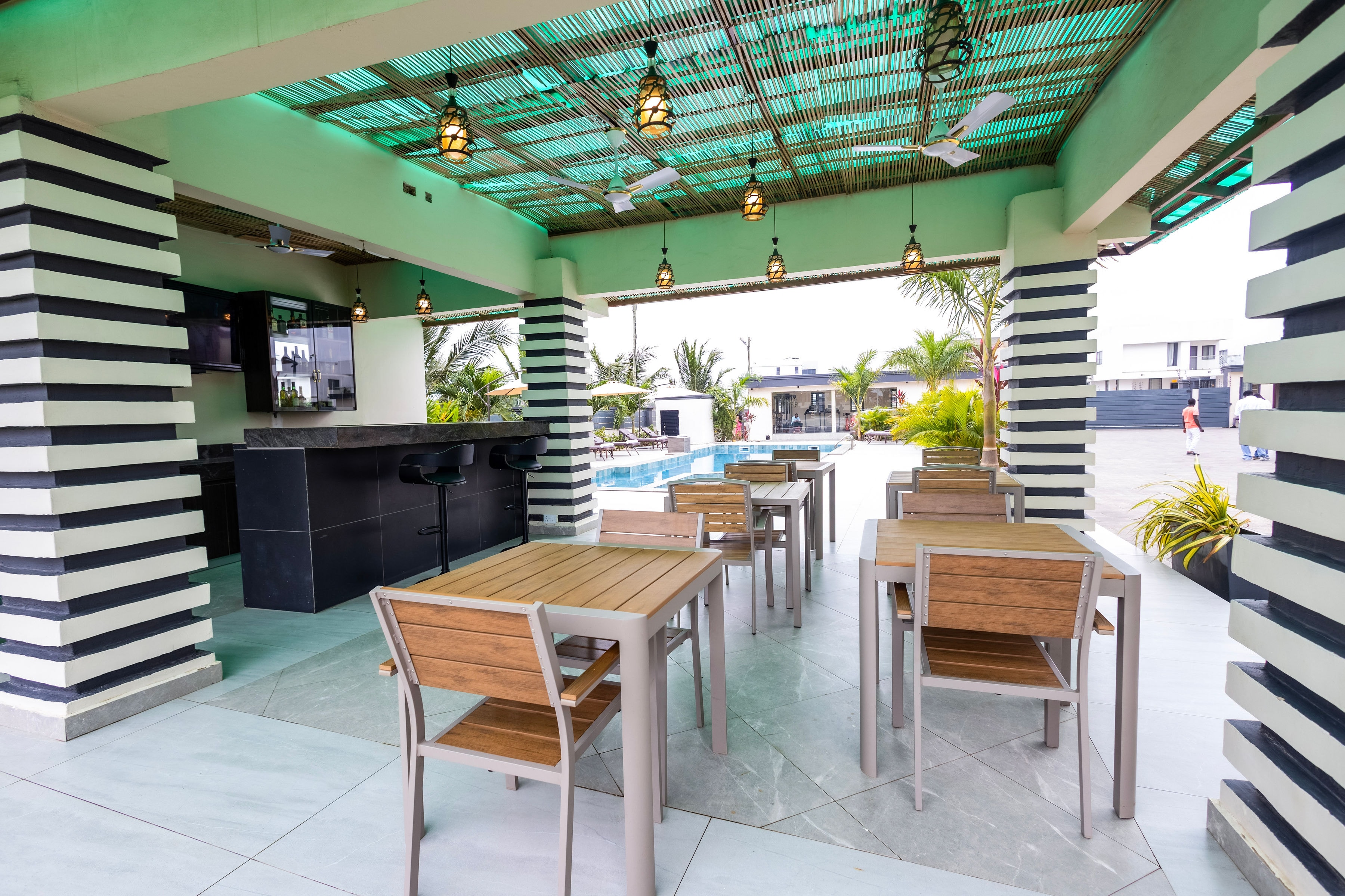 Teak tables and stools inside the bar pavilion, looking out to the pool