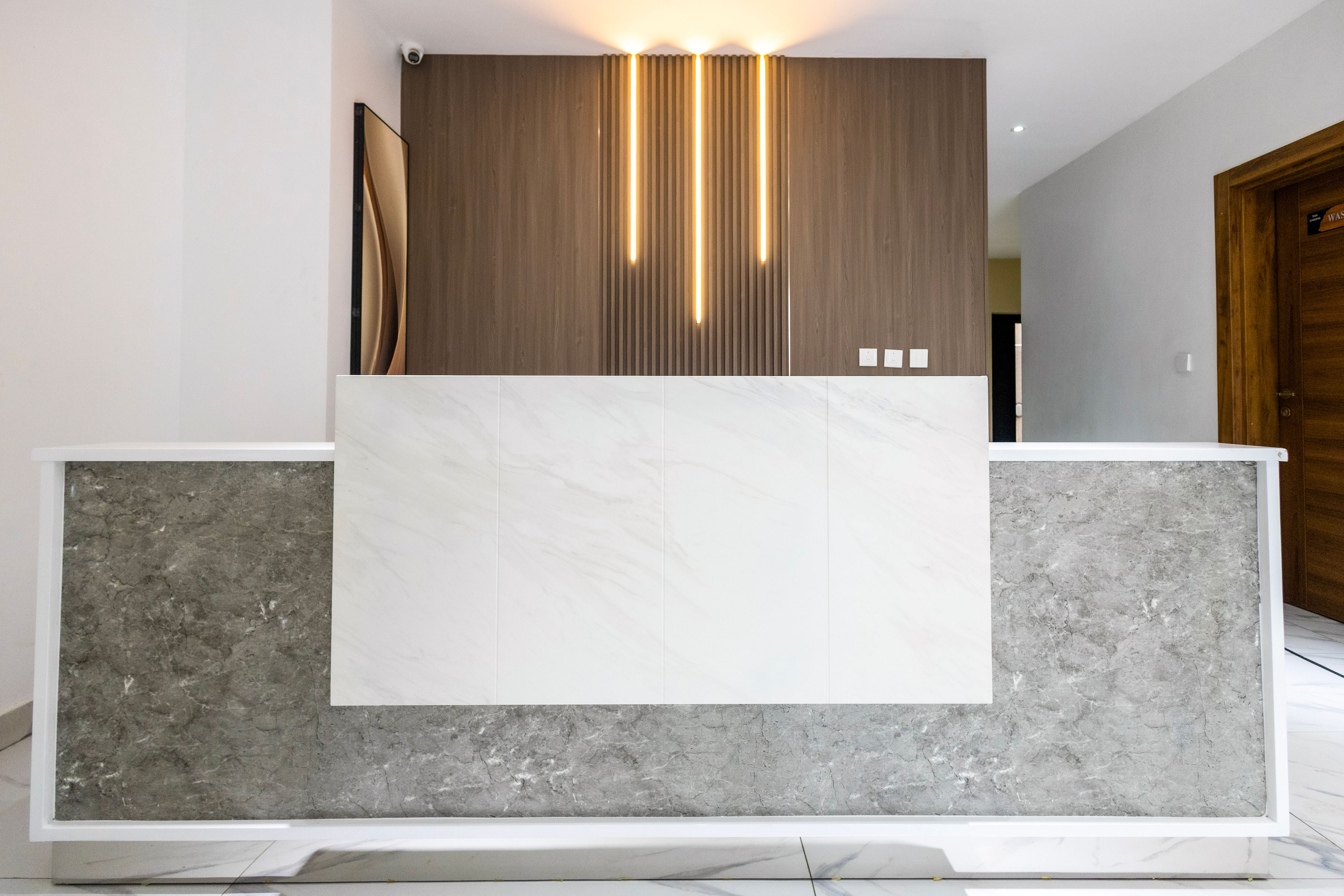 The marble reception desk beneath a backlit timber screen